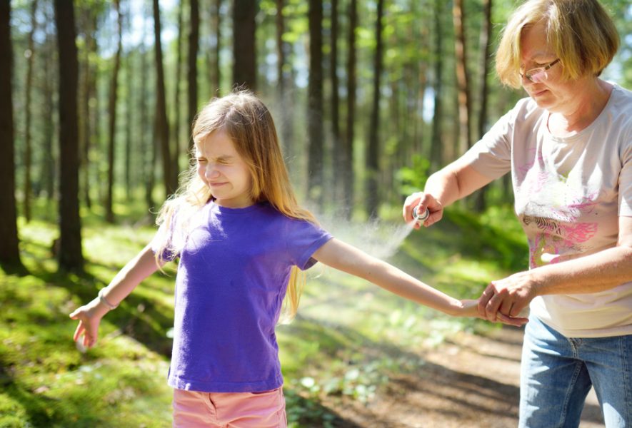 Laimo liga vaikams, moteris purškia repelentą vaikui